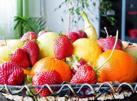 fruits basket in living room with strawberries, apples, pears, oranges, lemon, bananas