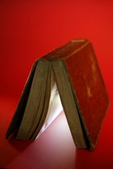 Old aged book close up, light glowing inside, over red background