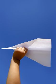 Paper airplane in children hand over sunny summer blue sky