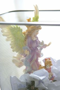 Atheist religion metaphor, angel saint figure in the office trash