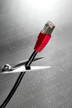 Cutting with scissors a network RJ45 red cable connection, silver background