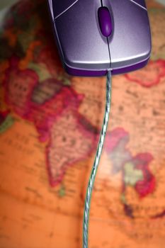 Computer wired mouse over the world colorful global earth map