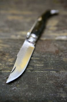 Open knife hand weapon over an aged wooden table