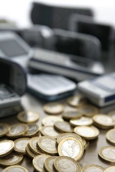 Assorted mixed mobile phones witt lots of euro coin in a studio still