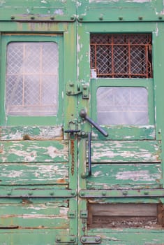 A derelict train with its door mechanism and barred and grilled windows. The entrannce to the mail section of the train.
