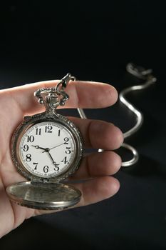 Antique vintage pocket watch on human hand over black