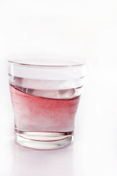 Glass of red color moving water, isolated on white background