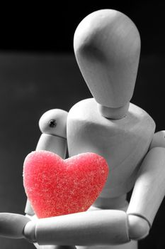 Wooden mannequin holding a red jelly candy heart shaped