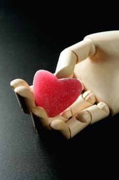 Wooden mannequin holding a red jelly candy heart shaped