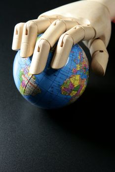 The world map in a wooden mannequin hand, black backgorund