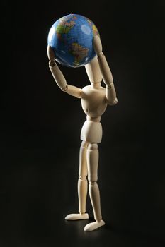 Wooden little mannequin holding a blue world map