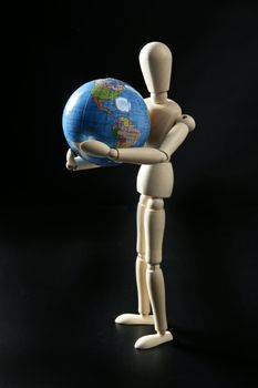 Wooden little mannequin holding a blue world map