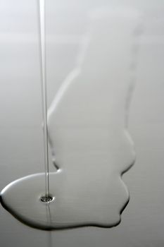 Liquid,transparent oil shape on a stainless steel metal surface