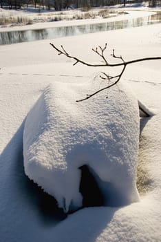 Two old wooden boats covered with snow resting near tree on the coast of the river.