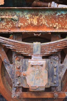 Close up detail of a rusty and peeling bogie from a derelict train carriage. Detail shows wheel and rusty suspension blocks.