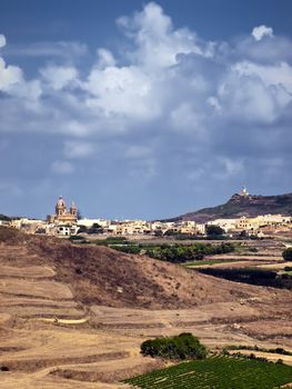 A church in Gozo and its lighthouse at background as seen from the medieval Citadel