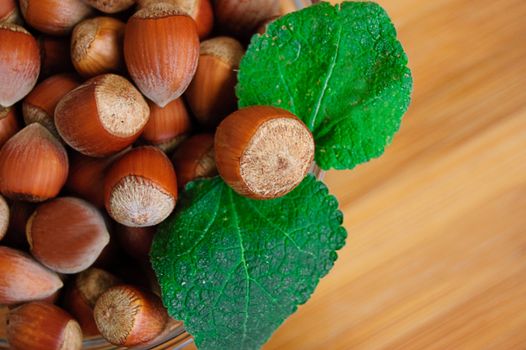 Some hazelnuts with leaves over wooden background