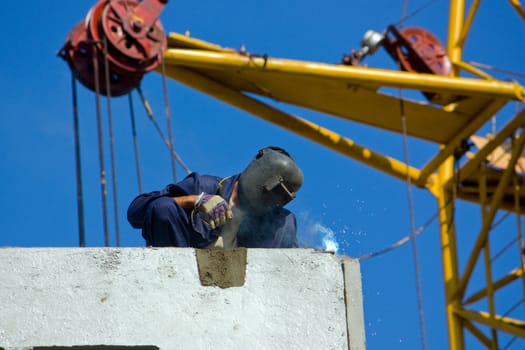 The welder on building of the house from ferro-concrete panels