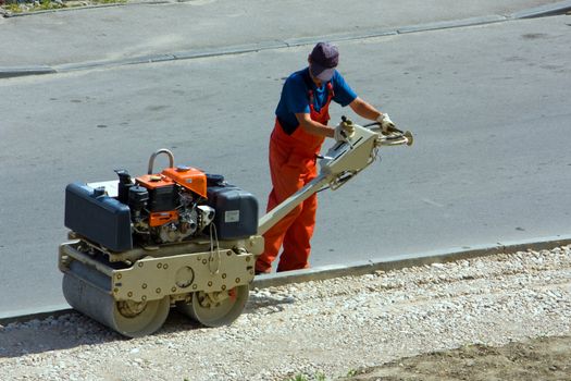 The worker builds sidewalk by means of the mechanical tool