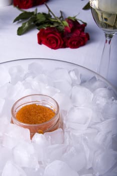 Red caviar in a glass jar surrounded by ice cubes and a rose
