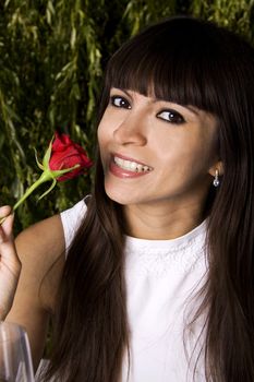 Beautiful Brazilian young woman smelling a rose