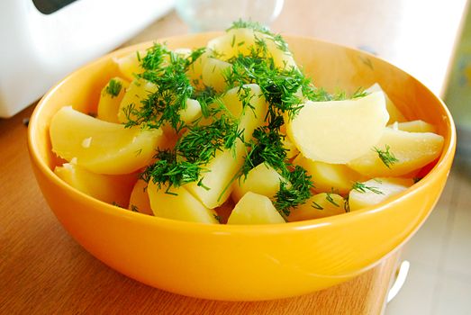 boiled potato with a fresh dill in a yellow dish