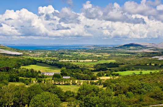 Landscape of County Clare, Ireland. Green fields in foreground and Galway Bay in the background. Beginings of the Burren can also be seen.