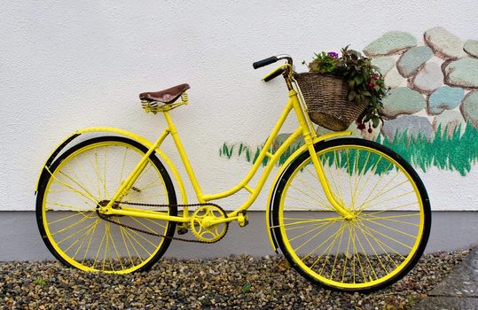 A yellow bike leaning on a white wall