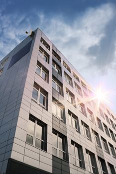 Grey office building and rays of sun in moody sky