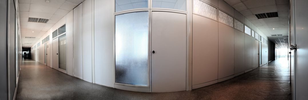 Long and curved grey corridor with closed office doors. Panoramic shot