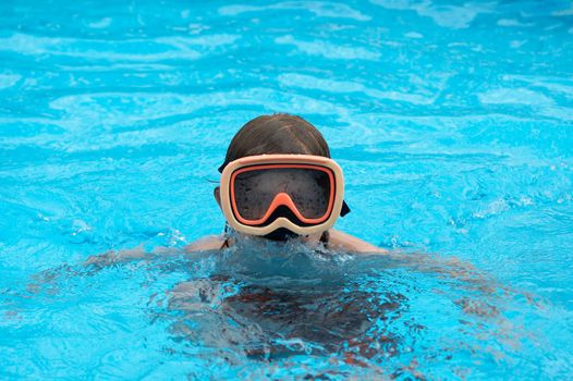 a young boy in pool with goggles on