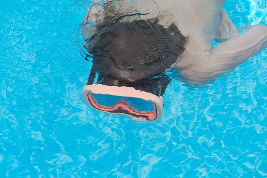 a young boy underwater with goggles on