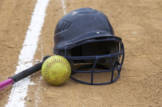a bat, softball, and helmet on a sports infield