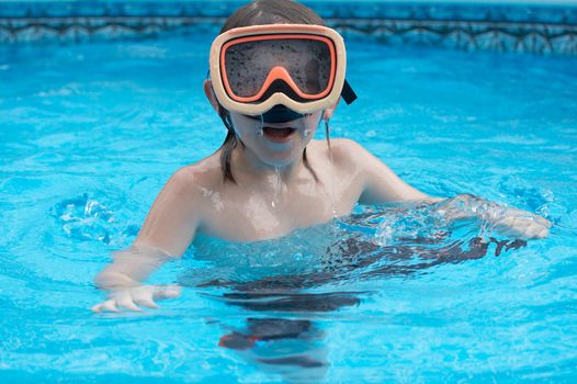 a young boy in pool with goggles on