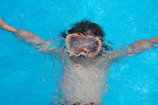 a young boy underwater with goggles on