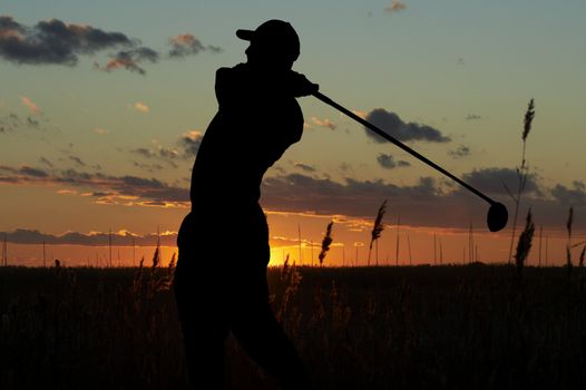 a silhouette of a golfer on a mourning sunset