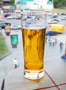 glass with beer on an a table and street background
