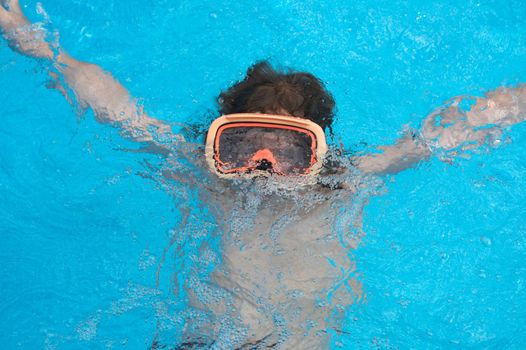 a young boy in pool with goggles on