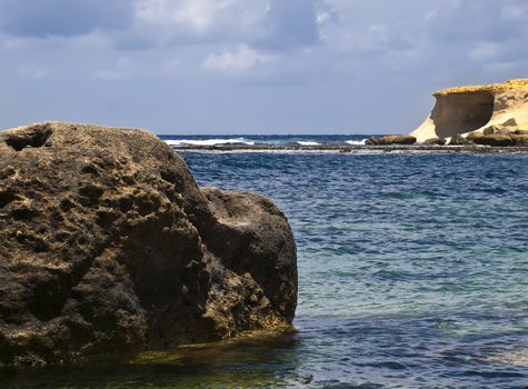 A highly textured lone rock lying in the sea in Gozo