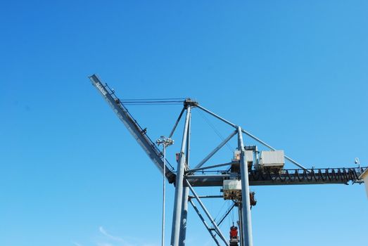 photo of heavy crane to load containers into ships against blue sky