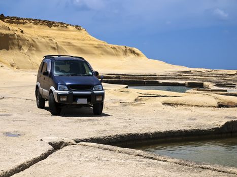 Offroad SUV lying on sandstone plains in Qbajjar in Gozo