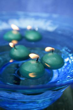 green candles over blue glass bowl of water