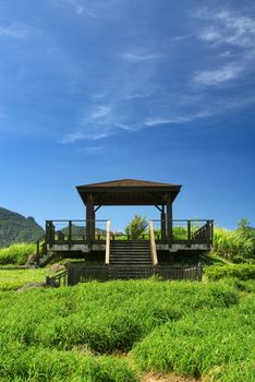 It is a pavilion on the grassland with blue sky.