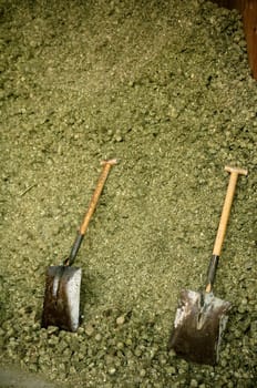 Two shovel in dry alfalfa, horses food, granary, barn.