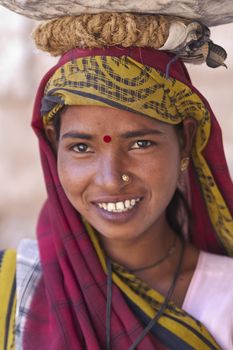 Indian woman labourer carrying metal bowl filled with cement  in Orchha, Madhya Pradesh, India