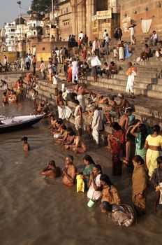 Crowds of people worshiping bathing in the sacred River Ganges at Varanasi, India