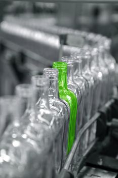 Bottles in a factory line, one different unique green