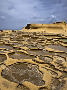 Ancient saltpanes from Roman times carved in sandstone in Qbajjar in Gozo