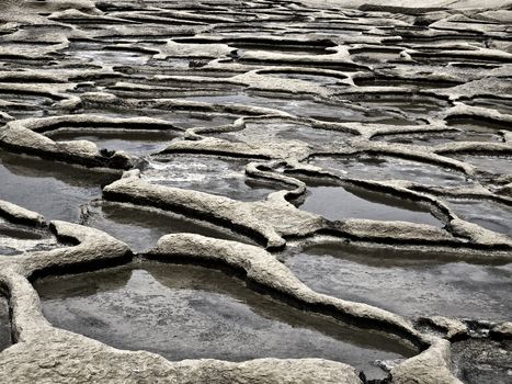 Ancient saltpanes from Roman times carved in sandstone in Qbajjar in Gozo