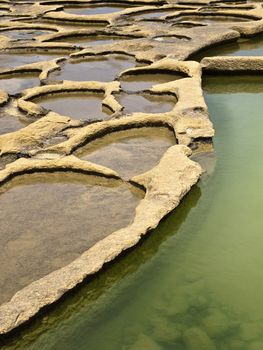 Ancient saltpanes from Roman times carved in sandstone in Qbajjar in Gozo